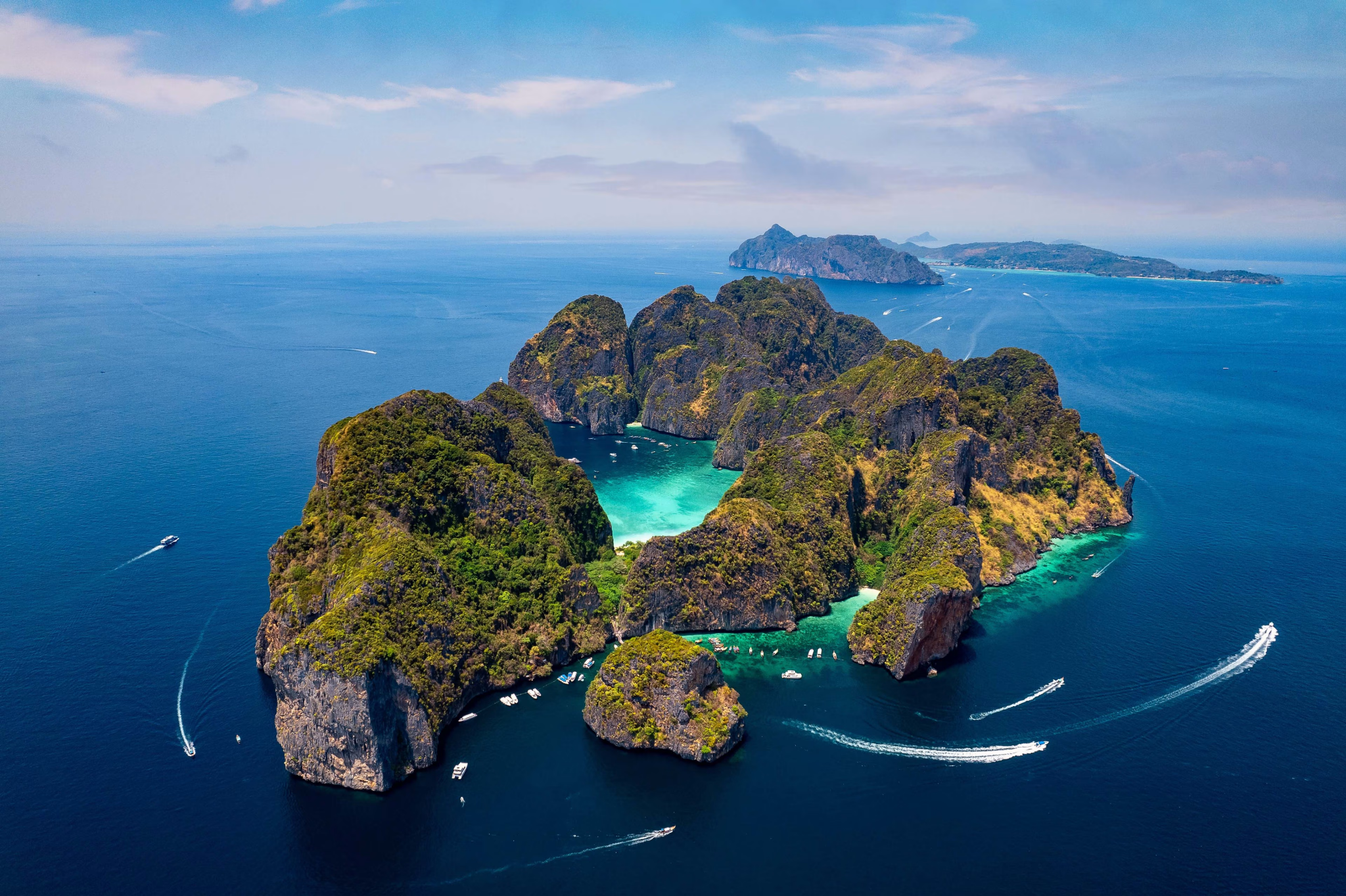 Aerial view of limestone islands, turquoise water and boats in Thailand