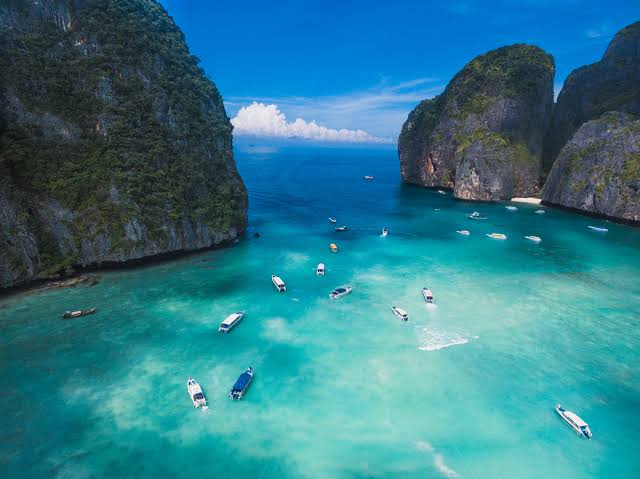 Boats on turquoise water between steep limestone cliffs